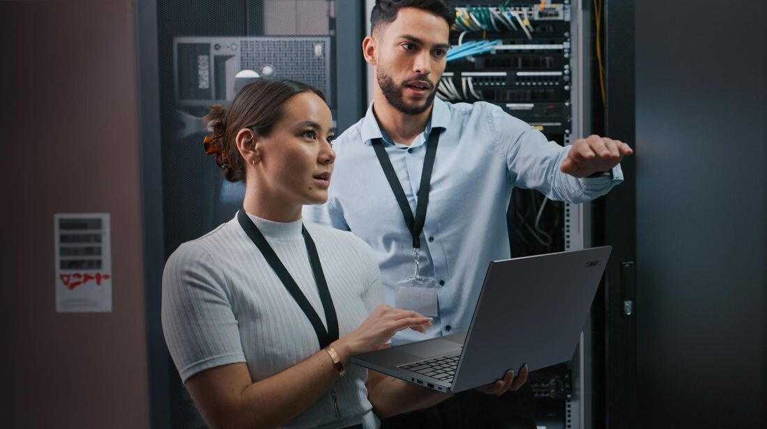 Dwoje ludzi stoi przed serwerem, trzymając laptopa ACER TravelMate P2.  - TPM 2.0 ACER ProShield Plus 