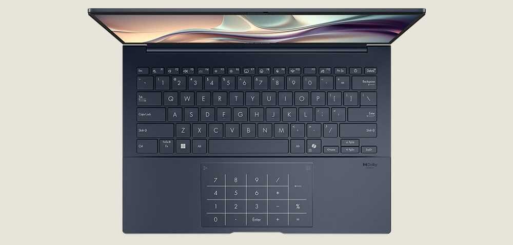 Widok z góry na klawiaturę laptopa ASUS Zenbook 14 z dużym touchpadem i podświetlanymi klawiszami, wyświetlacz z delikatną grafiką, funkcja cichej klawiatury.