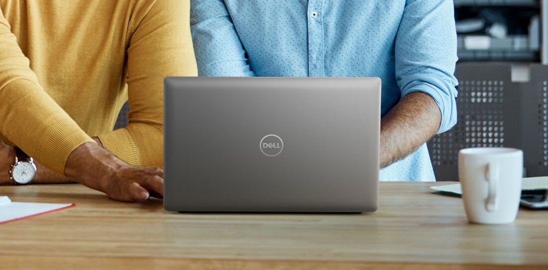 Dwie osoby pochylone nad srebrnym laptopem DELL Latitude przy drewnianym biurku, z kubkiem kawy i dokumentami w nowoczesnym biurze. - dysk SSD PCIe NVMe 4.0