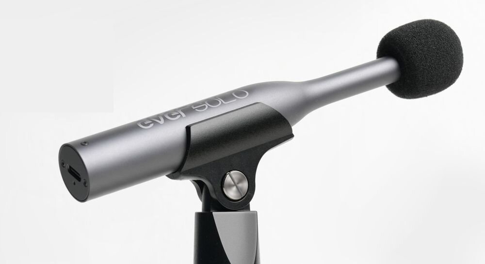 Na obrazie widoczny jest mikrofon z napisem \'ever SOLO\' na obudowie. Mikrofon ma czarną osłonę przeciwwietrzną i jest zamontowany na uchwycie.
