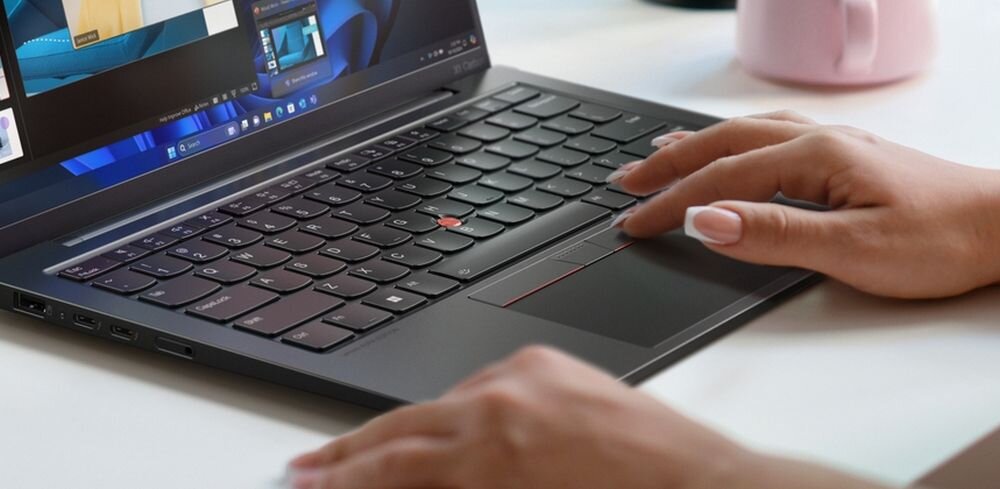 Dłonie obsługują laptop Lenovo ThinkPad z haptycznym touchpadem podczas precyzyjnej pracy przy biurku. - Haptyczny touchpad