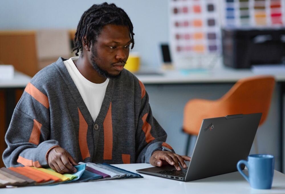 Laptop Lenovo ThinkPad otoczony wizualnymi falami dźwięku prezentuje technologię Dolby Atmos podczas pracy multimedialnej. - Głośniki stereo 2×2 W Dolby Atmos