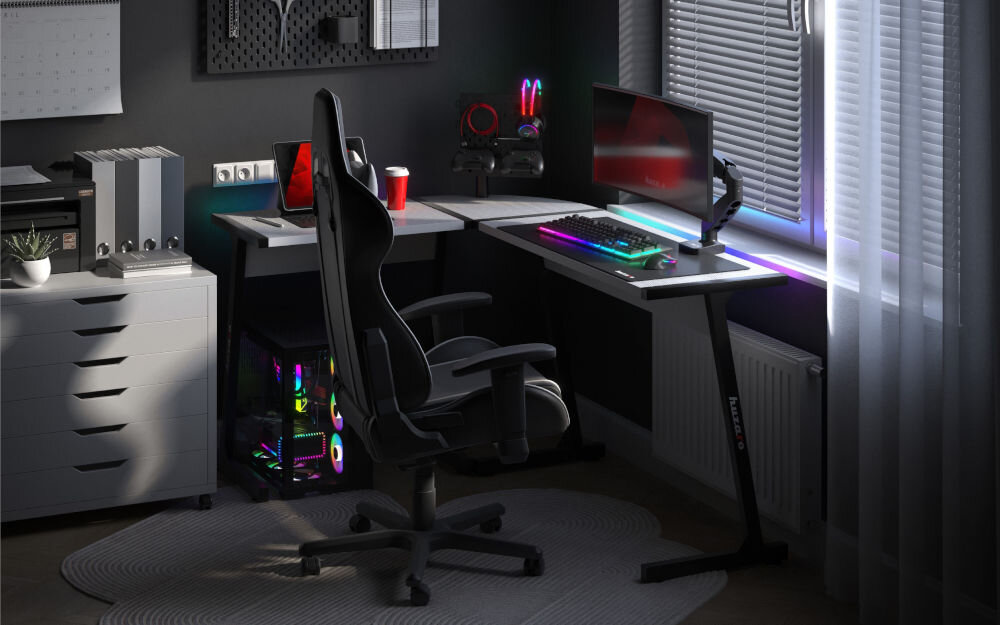 Biurko gamingowe HUZARO Hero 6.0 RGB Biały prezentacja biurka w pokoju o ciemnych ścianach na biurku akcesoria i komputer przy biurku fotel