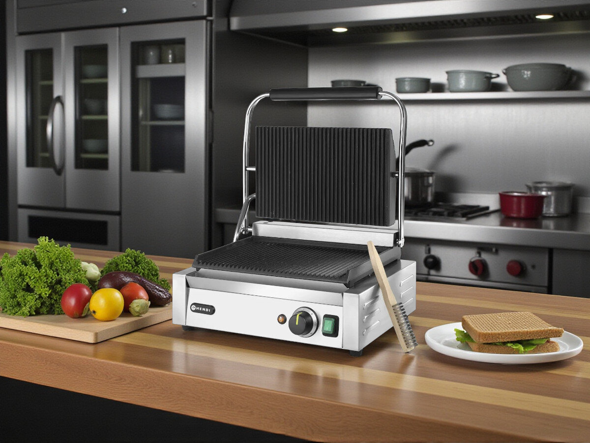 Grill elektryczny HENDI Panini 263655, kuchnia domowa, gastronomia, uniwersalność, szybkie przygotowanie, Otwarty grill Panini Hendi 263655, szczotka do czyszczenia, warzywa, kanapka i przybory kuchenne na blacie w tle.