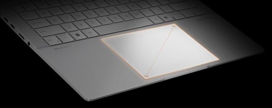 Touchpad laptopa ASUS VivoBook S 14 z widoczną żółtą ramką podświetlenia wokół obszaru dotykowego na czarnej powierzchni klawiatury - duży touchpad