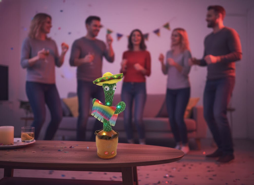 Zabawka interaktywna EXTRALINK Kaktus z sombrero EX.24237 prezentacja zabawki na stoliku w tle tańczący ludzie w pokoju pomysł na prezent wywołanie szerokiego uśmiechu interaktywne funkcje zabawny prezent