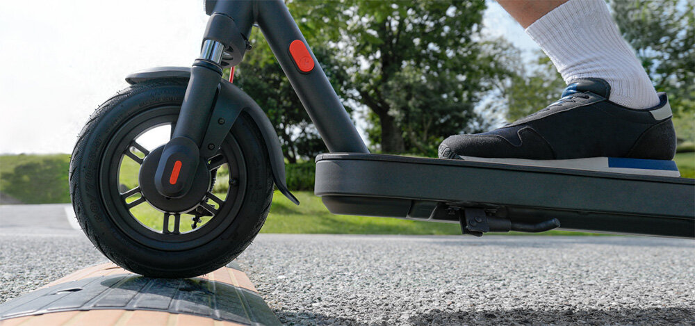 Hulajnoga elektryczna XIAOMI Scooter Elite 45km 400W 10 cali Czarny zbliżenie na przednie koło osoba jedzie po drodze wjeżdżając na niewielkie uniesienie 10-calowe koła bezdętkowe o niskim oporze toczenia duża przyczepność do podłoża opony bardzo dobrze absorbują wstrząsy i nierówności terenu stabilna wygodna jazda duża elastyczność płynne manewrowanie