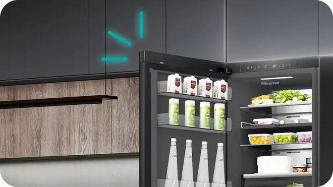 Otwarta czarna lodówka z widocznymi półkami wypełnionymi produktami spożywczymi, takimi jak kartony z napojami, butelki i warzywa. Na drzwiach lodówki widoczne jest logo \'Hisense\'.