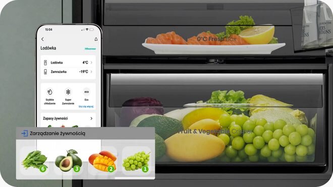 Obraz przedstawia wnętrze lodówki z różnymi warzywami i owocami w szufladzie oznaczonej jako \'Fruit & Vegetable Crisper\'. Obok lodówki widoczny jest ekran smartfona z aplikacją pokazującą temperaturę lodówki i zamrażarki oraz opcje zarządzania żywnością.