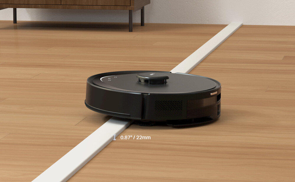 Czarny robot sprzątający porusza się po drewnianej podłodze, przekraczając próg o wysokości 0.87 cala / 22 mm.