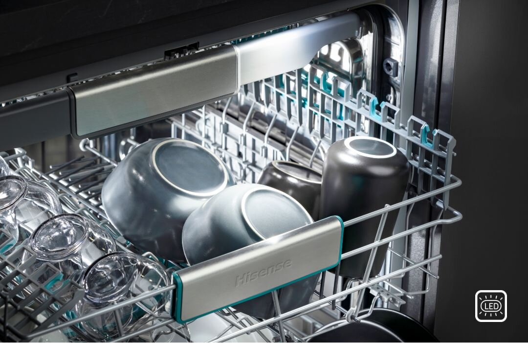 Wnętrze zmywarki z widocznymi naczyniami, takimi jak szklanki i miski, umieszczonymi w koszu. Na uchwycie kosza widnieje napis \'Hisense\'.