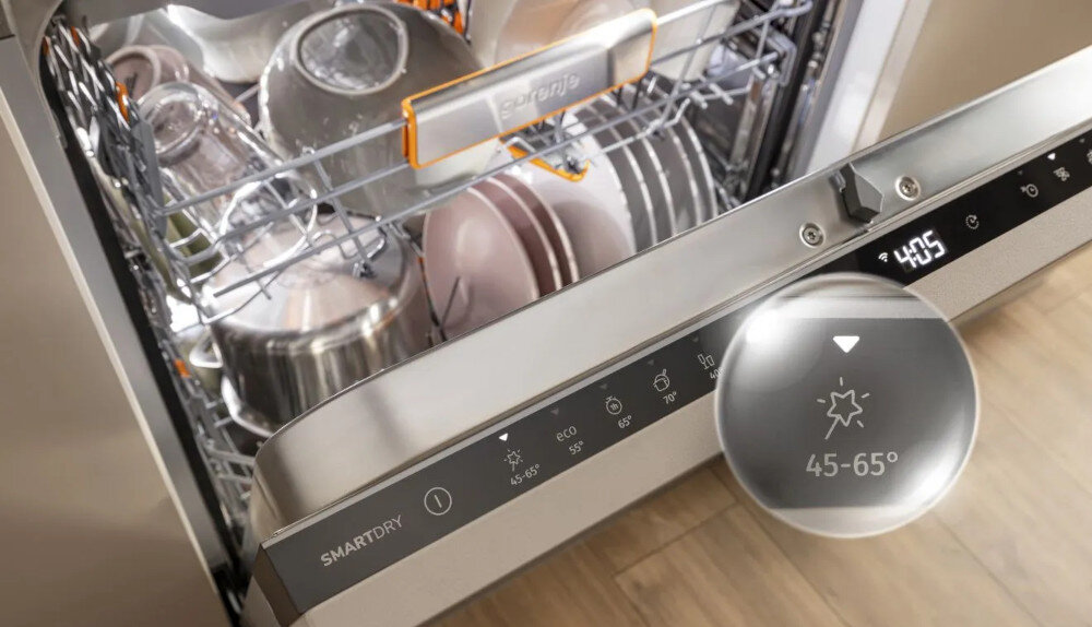 ZMYWARKA GORENJE GV693A65AD Na zdjęciu znajduje się zmywarka z uchylonym frontem, w której widać czyste naczynia ułożone w koszach. Panel sterowania pokazuje wybraną temperaturę mycia 45-65°C oraz funkcję SmartDry, a na wyświetlaczu widoczny jest czas pracy urządzenia czujniki automatyczne dostosowanie program zmywania szklane naczynia ciężkie naczynia efektywne zmywanie oszczędność wody oszczędność energii