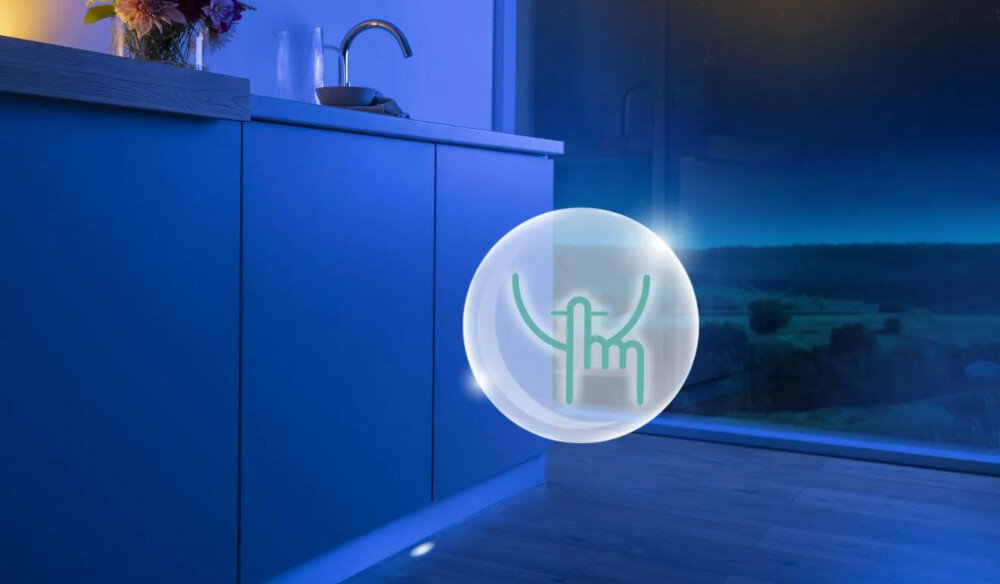 ZMYWARKA GORENJE GV693A65AD Na zdjęciu znajduje się kuchnia oświetlona niebieskim światłem z dużym oknem wychodzącym na nocny krajobraz. Na środku obrazu widnieje grafika przedstawiająca ikonę dotyku w przezroczystej kuli, co sugeruje intuicyjną obsługę urządzenia lub oświetlenia zmywarka cicha niski hałas 38dB 36dB izolacja premium cykl natryskiwania program nocny