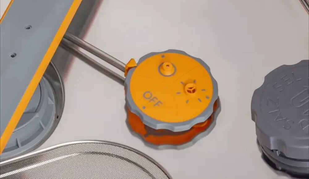 ZMYWARKA GORENJE GV693A65AD Na zdjęciu widoczny jest detal wnętrza zmywarki – żółto-szary zawór lub pokrętło oznaczone napisem „OFF”. Po prawej stronie znajduje się szara pokrywa pojemnika na sól, a w tle widać elementy ramion spryskujących i filtr dysze wysokie ciśnienie mocne natrysk trudne zabrudzenia garnki patelnie blachy mycie butelek regulowane dysze