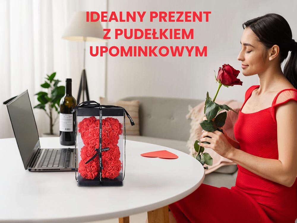 Miś EXTRALINK EX.24152 Czerwony, bateryjne, mobilne, włącznik, wygoda, kobieta siedzi przy stole w pokoju, wąchając różę a na stole stoi zapakowany miś