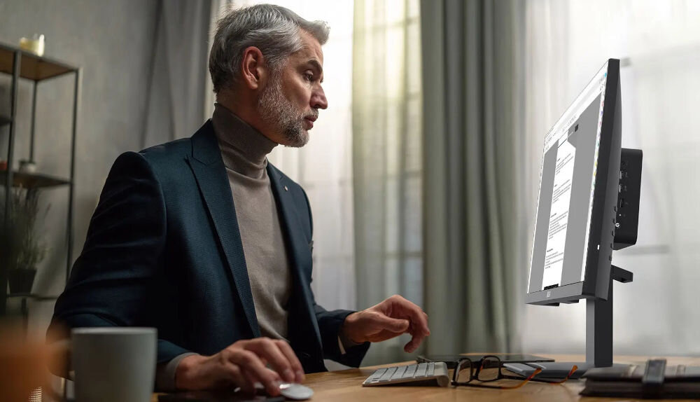 Monitor MSI Pro MP223 E2 21.45 cala 1920x1080px 100Hz 1 ms [MPRT] prezentacja monitora podczas użytkowania mężczyzna siedzący przy biurku EyesErgo poprawa ostrości obrazu stabilna podstawa komfort produktywność