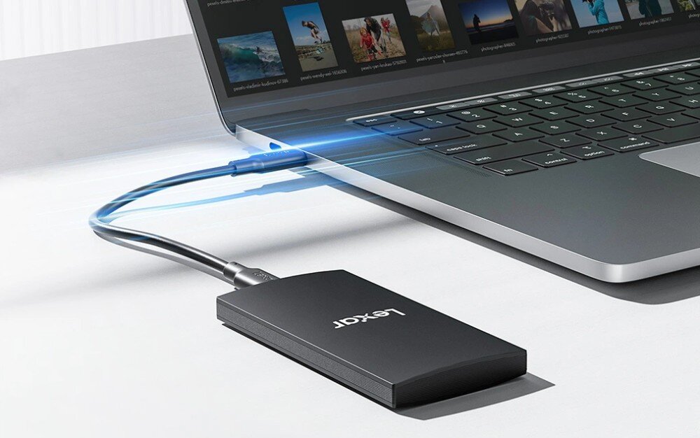 Dysk LEXAR SL300 Dysk podłączony kablem do komputera z niebieskimi smugami symbolizującymi transfer danych
