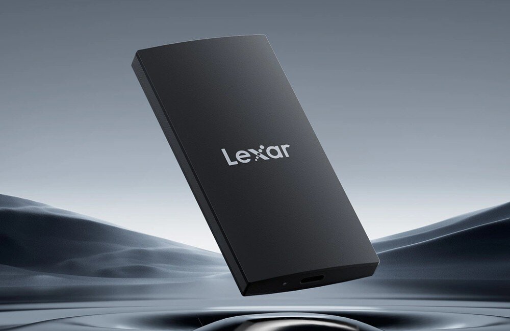 Dysk LEXAR SL300 Czarny dysk w ujęciu pionowym unoszący się nad pofalowaną szarą powierzchnią