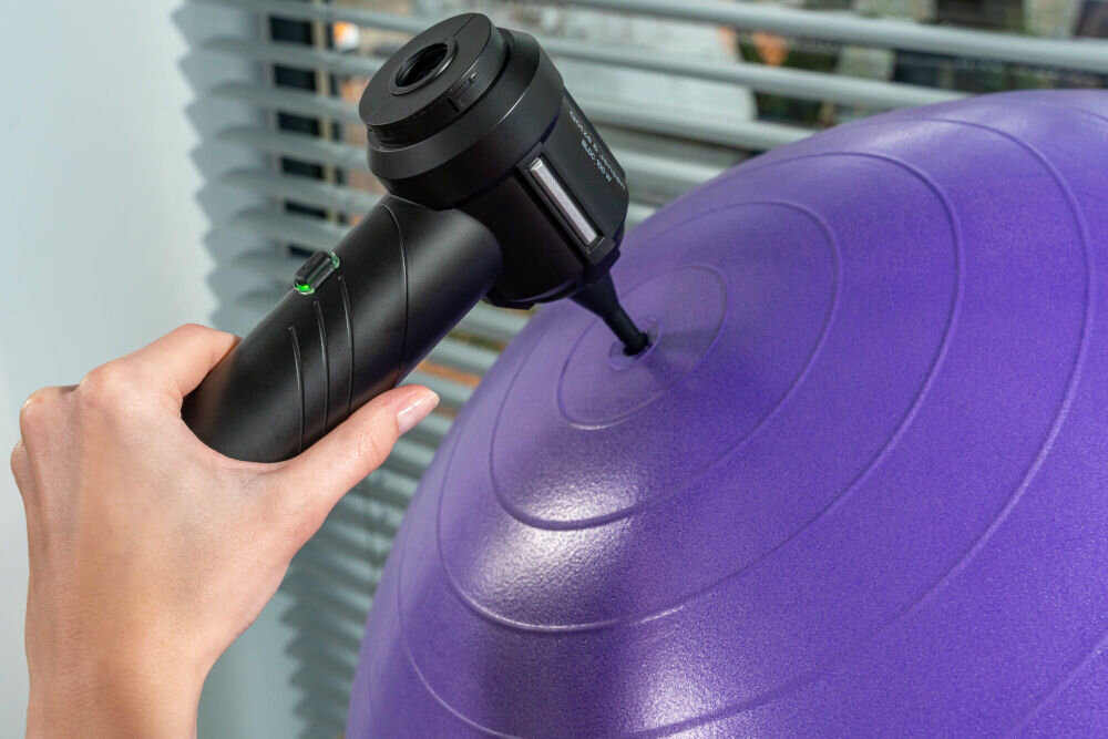 Odkurzacz ręczny GÖTZE & JENSEN HV400 Kompaktowy odkurzacz ręczny, używany jako pompka (dmuchawa) do nadmuchiwania dużej, fioletowej piłki gimnastycznej. Do gniazda piłki włożona jest wąska, stożkowa końcówka.