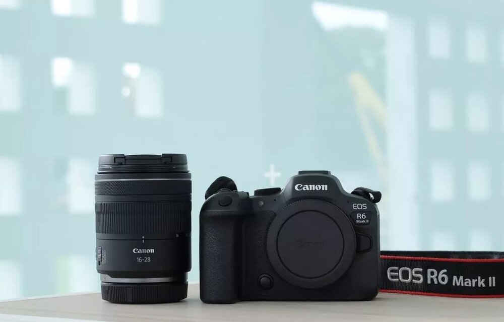 Obiektyw CANON RF 16-28 mm f-2.8 IS STM obok aparatu na blacie