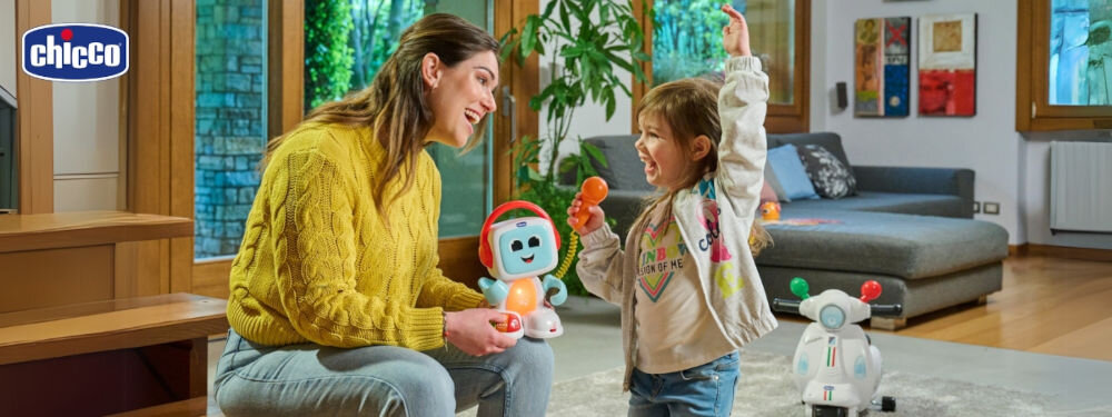 Zabawka edukacyjna CHICCO Happy Music Śpiewający robot Robit 00011853000000 radosna mama trzyma zabawkę robota świecące elementy dziecko trzyma mikrofon radośnie śpiewa nauka przez zabawę