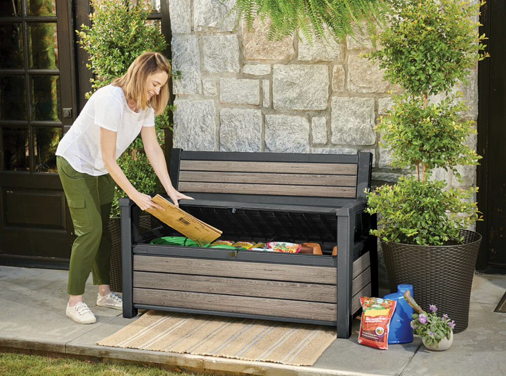 Ławka ogrodowa KETER Deco Garden Bench Popielaty, ławka, ogród, schowek, relaks, Kobieta odpoczywająca na ławce ze schowkiem w ogrodzie obok roweru.