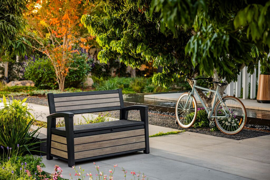 Ławka ogrodowa KETER Deco Garden Bench Popielaty, UV, deszcz, odporność, kolory, Brązowa ławka Keter z teksturą drewna na patio z rowerem.