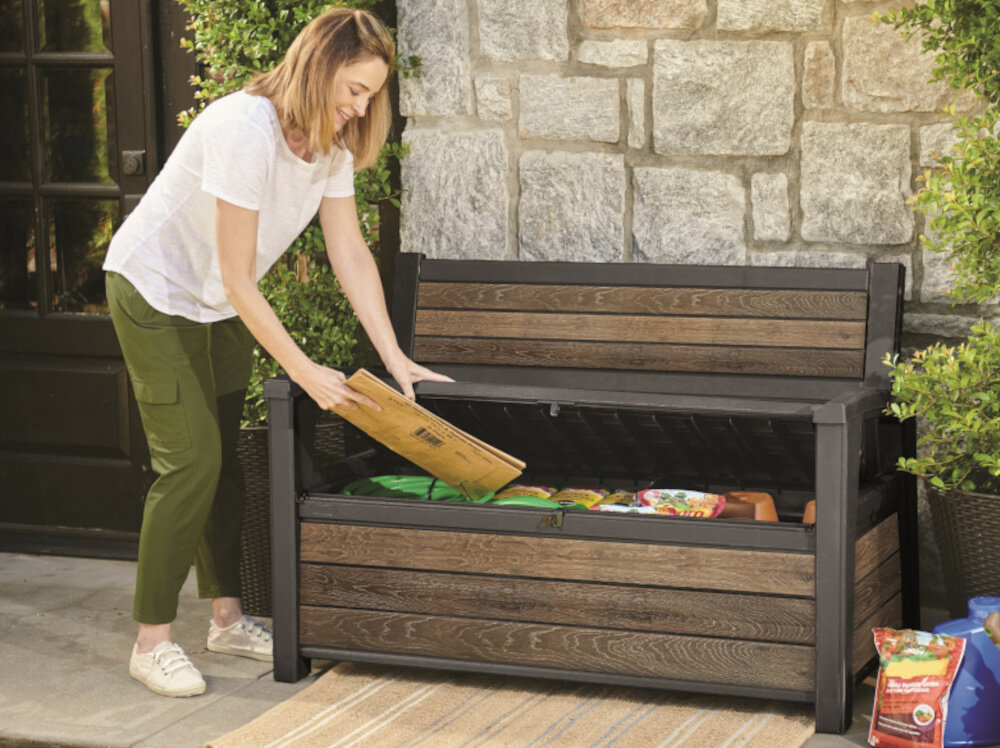 Ławka ogrodowa KETER Deco Garden Bench Szary ławka z otwartą pokrywą w środku różne rzczy osoba trzyma w dłoni złożony karton prosty system montażu nie wymaga specjalistycznych narzędzi przejrzysta instrukcja lekka konstrukcja waga 14,8 kg łatwe przestawianie szybkie i wygodne sposoby aranżacji przestrzeni wygoda praktyczność