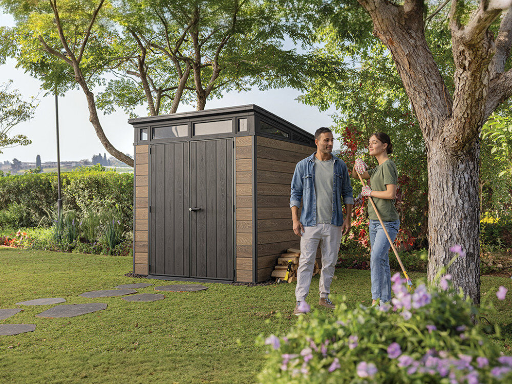 Domek narzędziowy KETER Penthouse Signature Collection 259814, ogród, porządek, luksus, styl, para stoi plecami do domku stojącego w ogrodzie