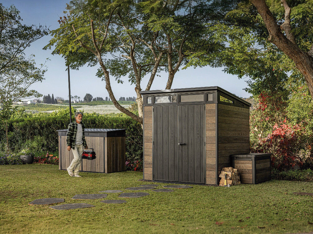 Domek narzędziowy KETER Penthouse Signature Collection 259814, DecoCoat, drewno, tekstura, trwałość, mężczyzna idzie przez ogród, obok stojący domek keter w ogrodzie