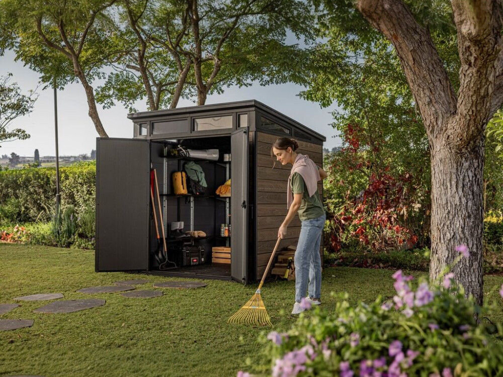 Domek narzędziowy KETER Penthouse Signature Collection 259814, wymiary, pojemność, kosiarka, miejsce, kobieta grabi trawnik w ogrodzie, w tle domek keter
