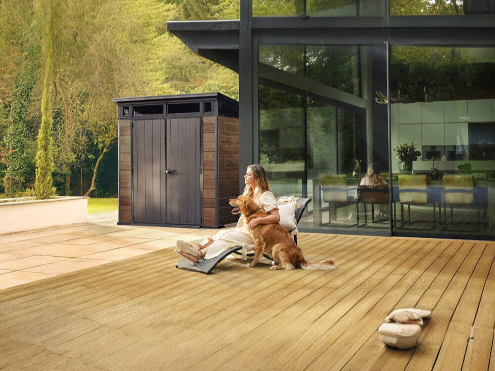 Domek narzędziowy KETER Penthouse Signature Collection 259814, wentylacja, świeżość, wilgoć, powietrze, kobieta leży na leżaku na tarasie, w tle domek keter