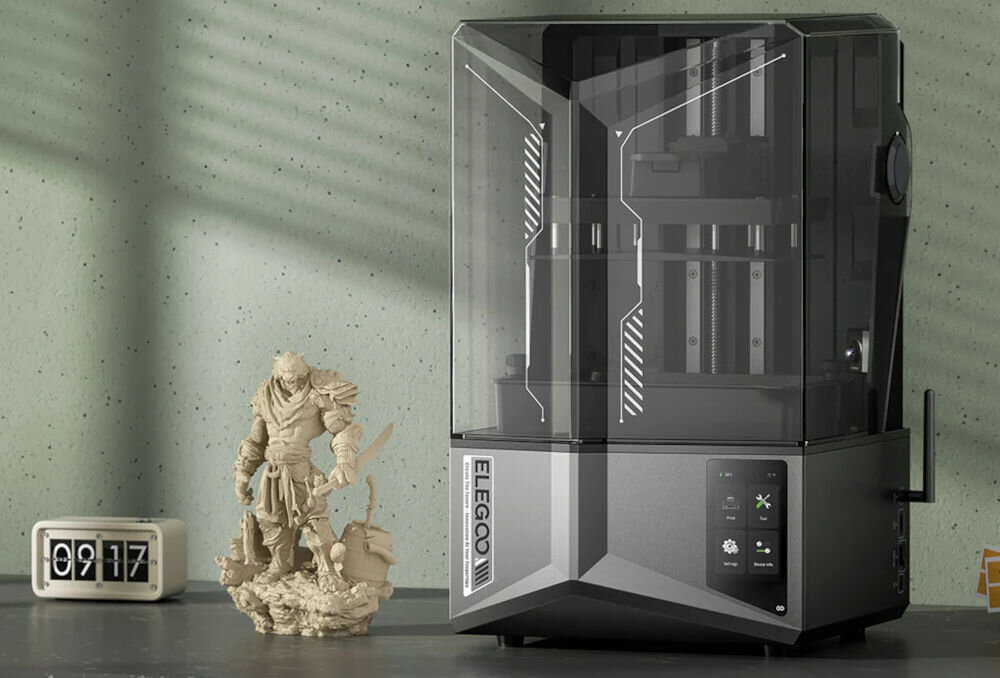 Drukarka 3D ELEGOO Saturn 4 Ultra Wi-Fi  prezentacja drukarki na półce zielona ściana z cieniem w tle obok wydrukowana figurka