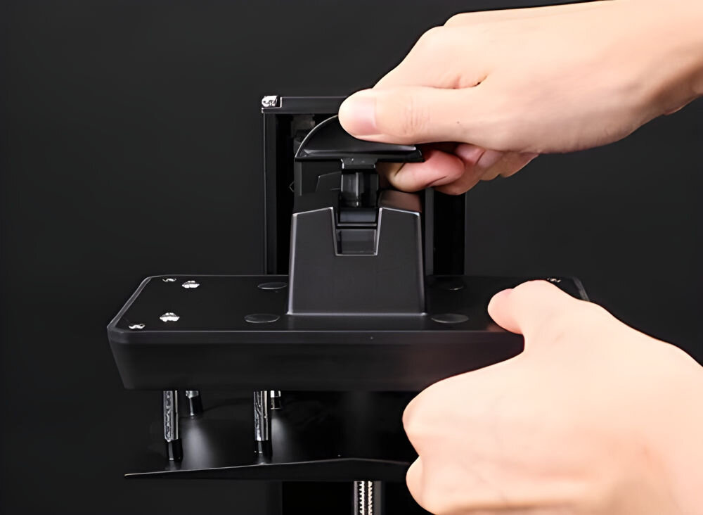 Drukarka 3D ELEGOO Mars 5 prezentacja szybkiego montażu ręce wkładające platformę szare tło system szybkiego zwalniania sprawny demontaż platformy stabilne zamocowanie