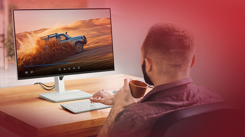 Monitor LENOVO L24m-4A 23.8 cali 1920x1080px IPS 100Hz 1 ms [MPRT] prezentacja monitora w pokoju mężczyzna siedzący przy biurku z kubkiem odświeżanie 100 Hz brak opóźnień i zakłóceń czytelny i dynamiczny