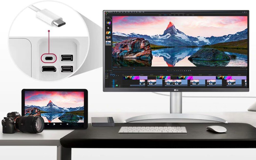 Monitor LG 27UP850K-W Monitor stoi na biurku obok tabletu i aparatu, na ekranie widać program do edycji wideo z ujęciem gór i jeziora, a w powiększeniu pokazane są porty USB-C i USB z tyłu urządzenia, porty, USB-C, zasilanie, złącza