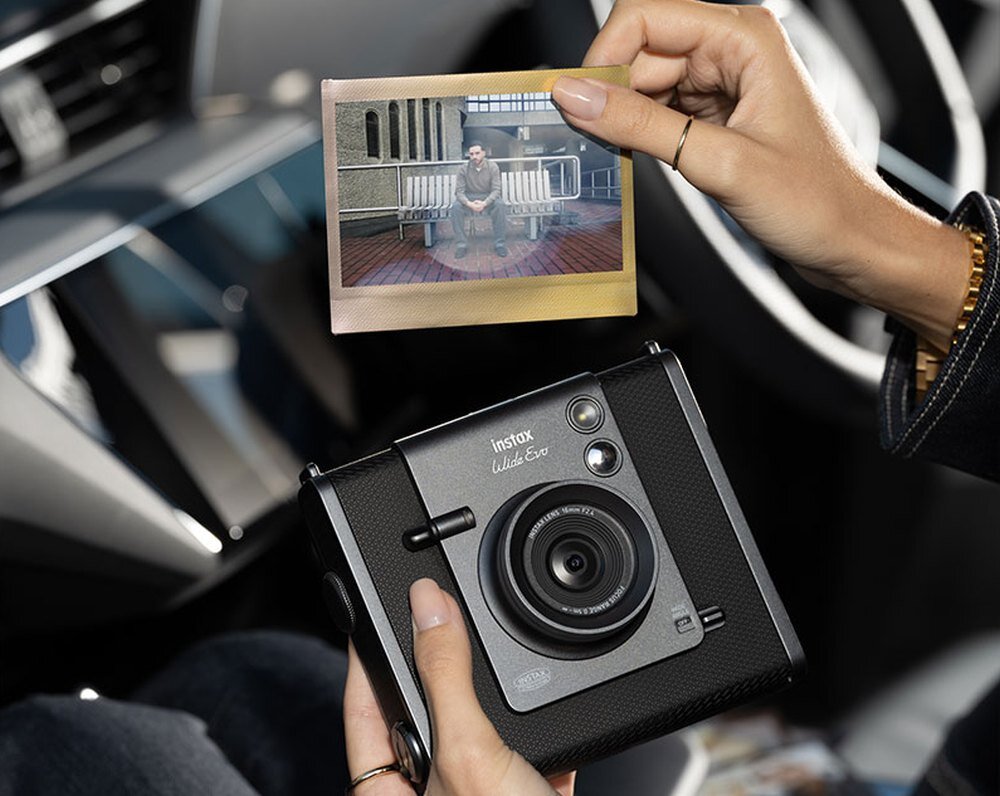 Aparat FUJIFILM Instax Wide Evo trzymany w samochodzie przez modelkę