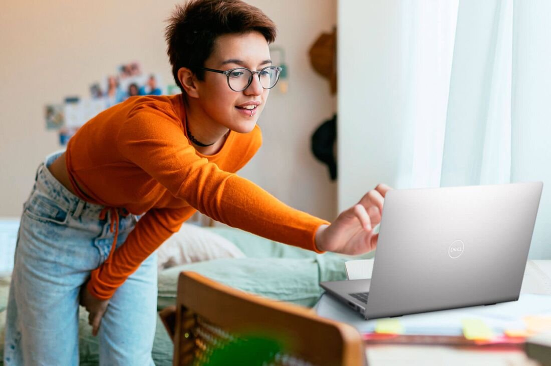 Młoda kobieta trzyma w rękach laptop DELL Inspiron 3530.   - Komfortowa komunikacja, Wbudowana kamera HD 