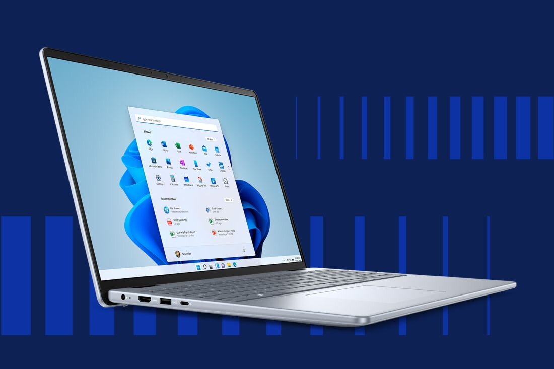 Laptop Dell Inspiron 5640 z wyświetlaczem prezentującym pulpit systemu Windows 11, srebrna klawiatura, cienkie ramki ekranu, granatowe tło z pionowymi liniami. - Windows