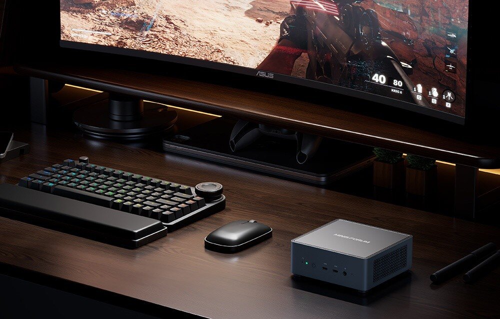 Komputer MINISFORUM Venus UM790 Pro Stacja MINISFORUM na biurku gracza pod monitorem, obok klawiatury mechanicznej i myszki.
