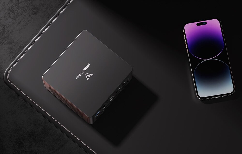 Komputer MINISFORUM EliteMini UM890 Pro Widok z góry na Minisforum leżące na podkładce obok smartfona, podkreślający kompaktowy rozmiar urządzenia.