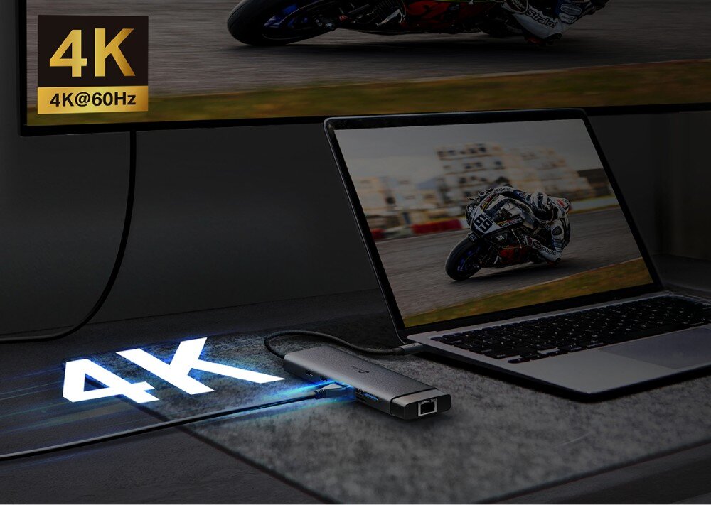 Hub TP-LINK UH9120C Laptop oraz duży monitor wyświetlający ten sam obraz wyścigu motocyklowego, z widocznym napisem '4K przy 60Hz' przy porcie HDMI adaptera