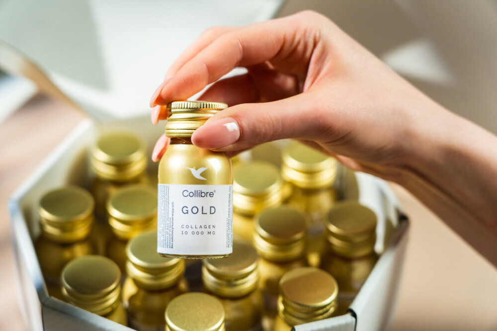 Kolagen COLLIBRE Gold shot 15 x 30 ml osoba wyciąga jedną buteleczkę z pudełka zestaw 15 buteleczek z kolagenem pojemność 30 ml każda