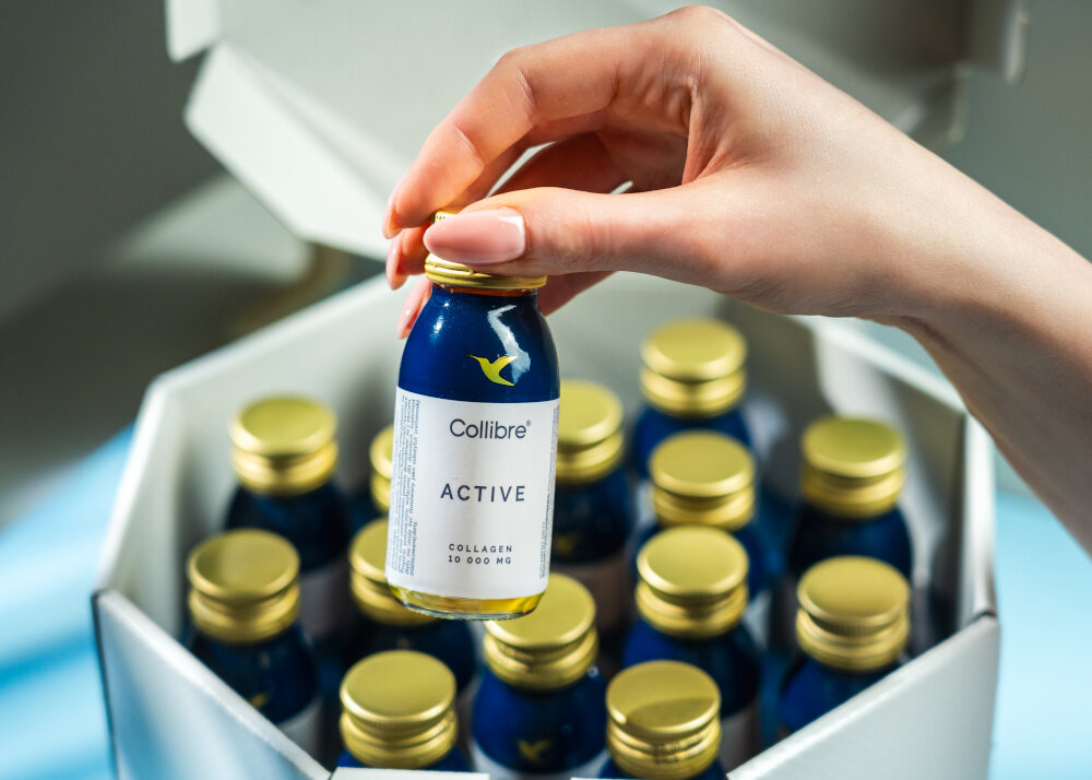Kolagen COLLIBRE Active shot 15 x 60 ml osoba wyciąga jedną buteleczkę z pudełka zestaw 15 buteleczek z kolagenem pojemność 60 ml każda