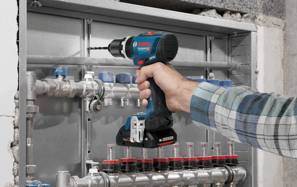 Wiertarko-wkrętarka BOSCH Professional GSB 18V-65 06019N3300 pomieszczenie metalowa konstrukcja osoba trzyma wiertarko-wkrętarkę w dłoniach wierci otwór w konstrukcji szybkozaciskowy uchwyt wiertarski 13 mm sprawna wymiana wierteł i bitów bez użycia dodatkowych kluczy zakres mocowania 1,5–13 mm cienkie wiertła do precyzyjnych otworów większe akcesoria do cięższych prac