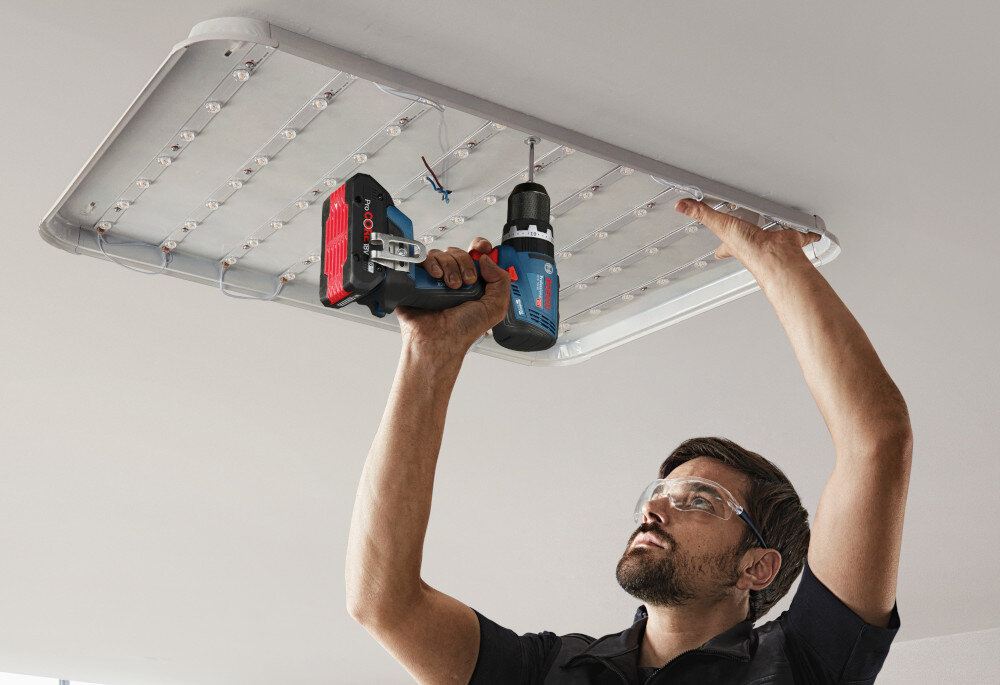 Wiertarko-wkrętarka BOSCH Professional GSB 18V-65 06019N3303 pomieszczenie osoba przykręca lampę do sufitu waga około 1,12 kg smukła dobrze wyprofilowana rękojeść środkowa pokrycie Softgrip z antypoślizgowego miękkiego materiału długość korpusu wynosząca 175 mm stabilność chwytu ogranicza ślizganie się dłoni