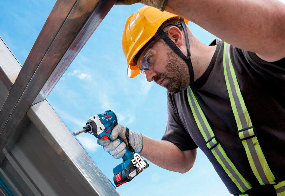 Klucz udarowy BOSCH Professional GDR 18V-215 06019N2002 plac budowy dach osoba wkręca śrubę w metalową ramę okienną efektywna praca z elementami metalowymi wkręcaniem śrub samowkręcających w blachy metalowe o grubości 3 mm śrub maszynowych M8 w gwintowanych bloczkach śrub samogwintujących w cieńszych blachach do dokręcania i odkręcania nakrętek do rozmiaru M10