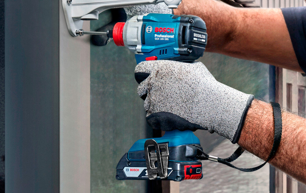 Klucz udarowy BOSCH Professional GDX 18V-285 06019N2100 osoba dokręca śrubę w ścianie widok od tyłu lekko pod skosem obudowa odporna na uszkodzenia ergonomiczny kształt rękojeści antypoślizgowa powłoka waga około 1,1 kg bez akumulatora większy komfort i lepsza kontrola narzędzia