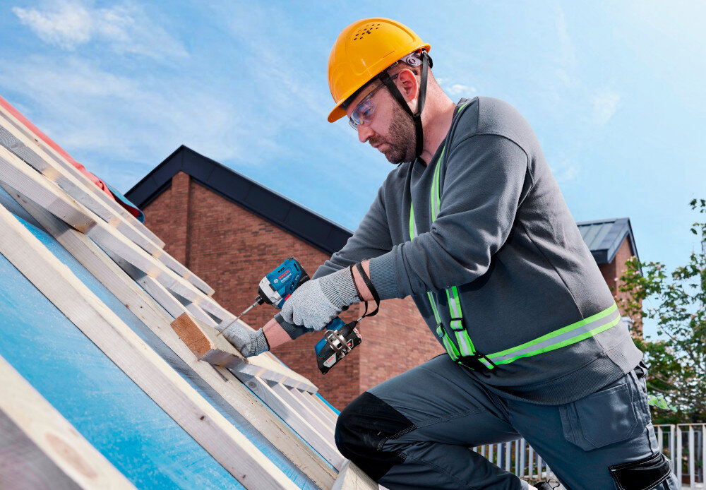 Klucz udarowy BOSCH Professional GDR 18V-215 06019N2022 plac budowy dach osoba wkręca śrubę w drewnianą ramę okienną w tle niebo dachy domów praca w betonie funkcja udaru liczby udarów w zakresie od 0 do 3800 uderzeń na minutę dwustopniowa regulacja (0-3000 ud/min, 0-3800 ud/min) dopasowanie parametrów do różnych zada