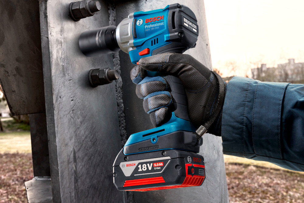 Klucz udarowy BOSCH Professional GDS 18V-350 06019M5020 plac budowy osoba dokręca śruby na metalowej konstrukcji do szybkiego i skutecznego dokręcania oraz odkręcania śrub i nakrętek wysoki moment obrotowy mechanizm udarowy eliminuje konieczność stosowania dźwigni lub dużej siły fizycznej
